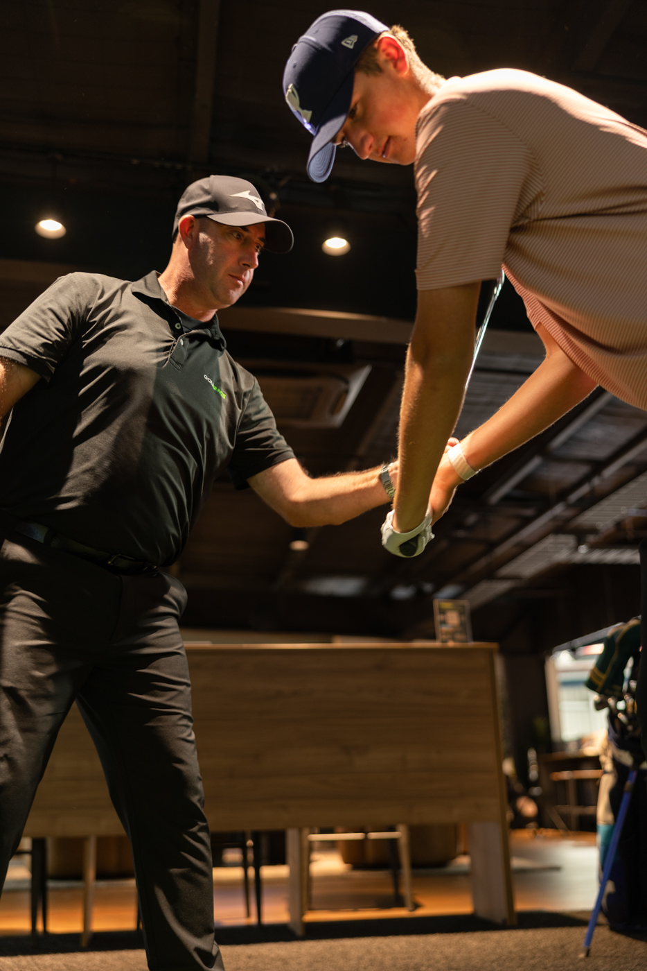 GolfSpace PGA coach guiding a player's grip and wrist position during a one-on-one session.