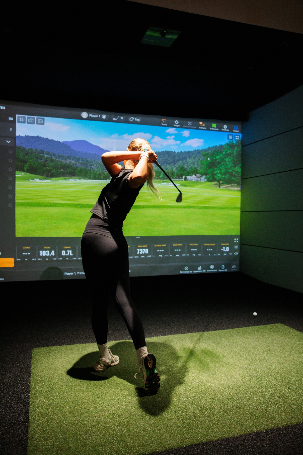 Golfer mid-swing with live TrackMan carry and total data on screen.