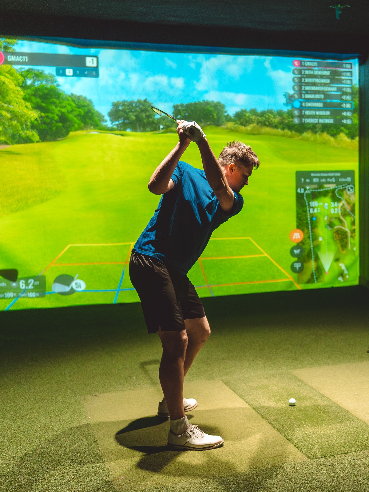 Focused golfer at the top of the backswing on the GolfSpace simulator.