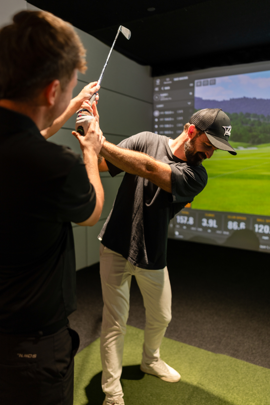GolfSpace PGA coach checking a player's club position at the top of the backswing in a simulator bay.